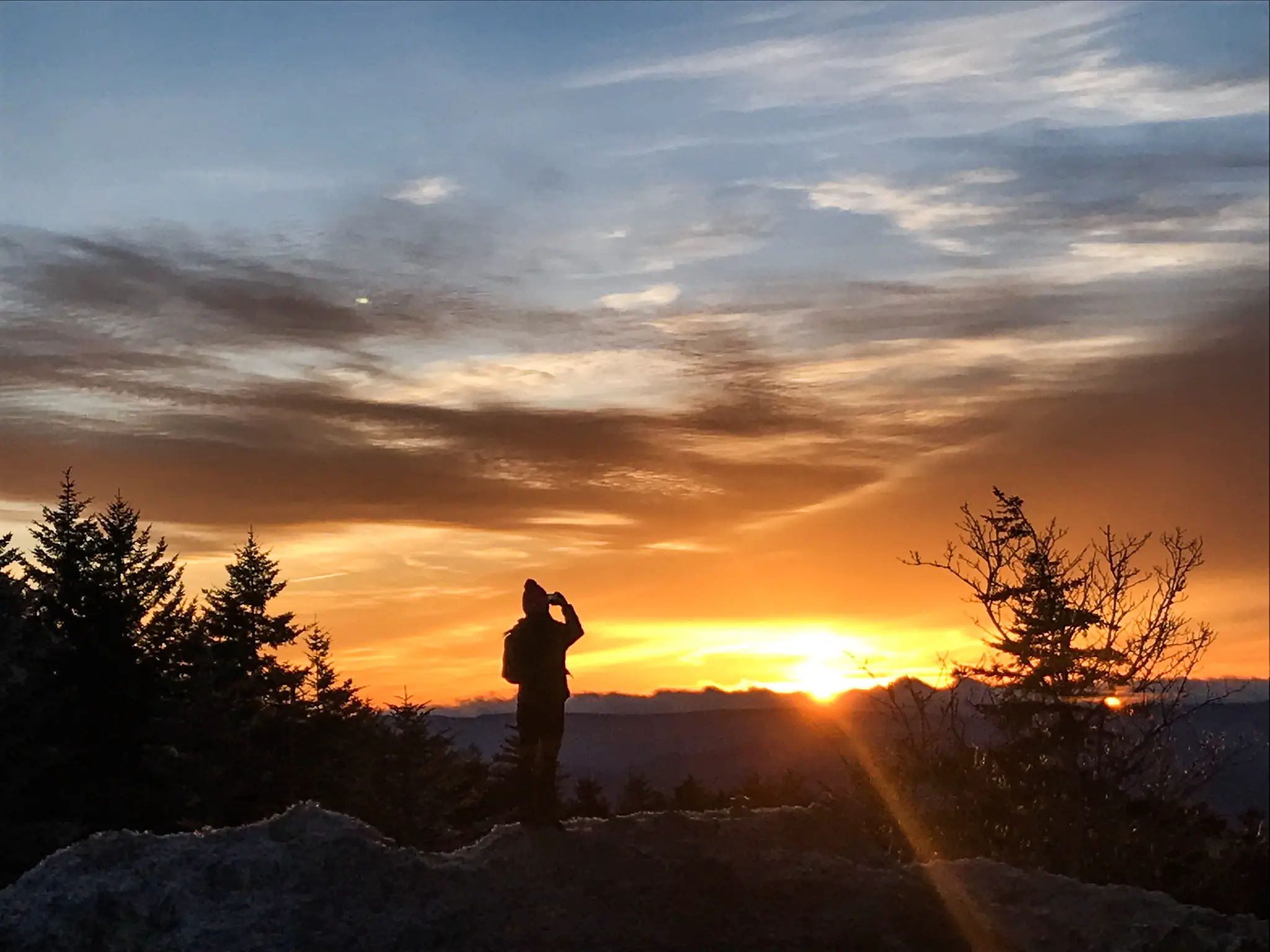 Girl photographing sunset in mountains