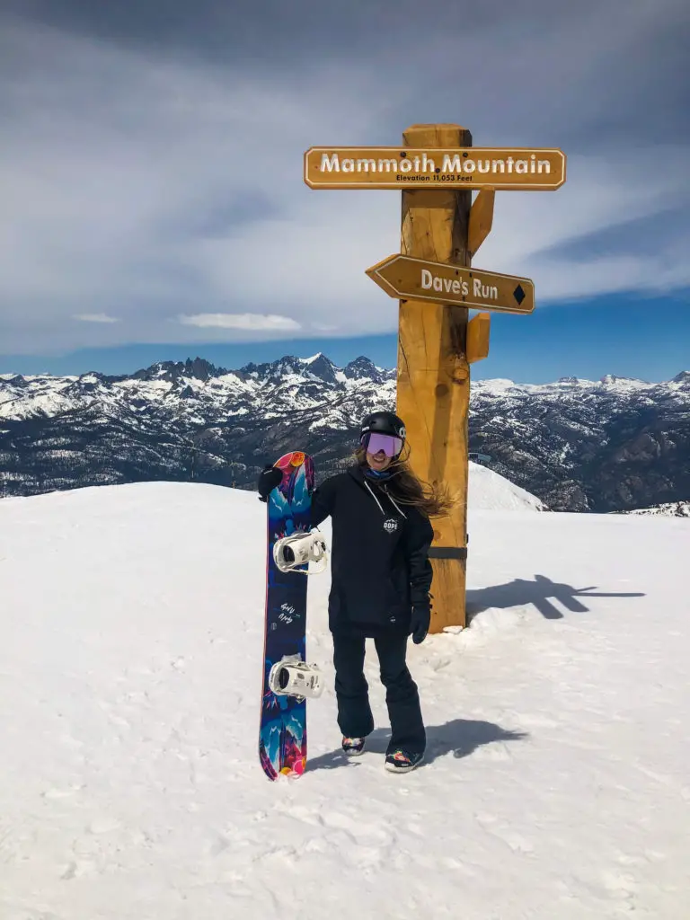 Girl in front of Mammoth sign with snowboard