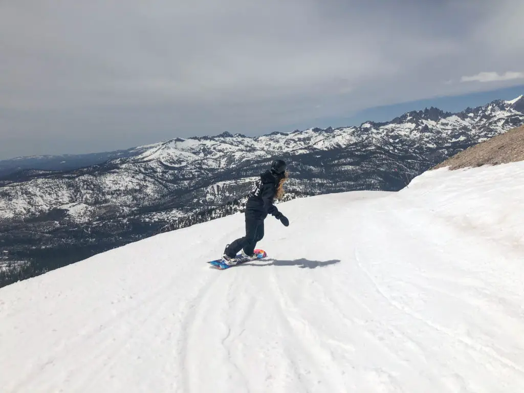 girl snowboarding with mountains in background